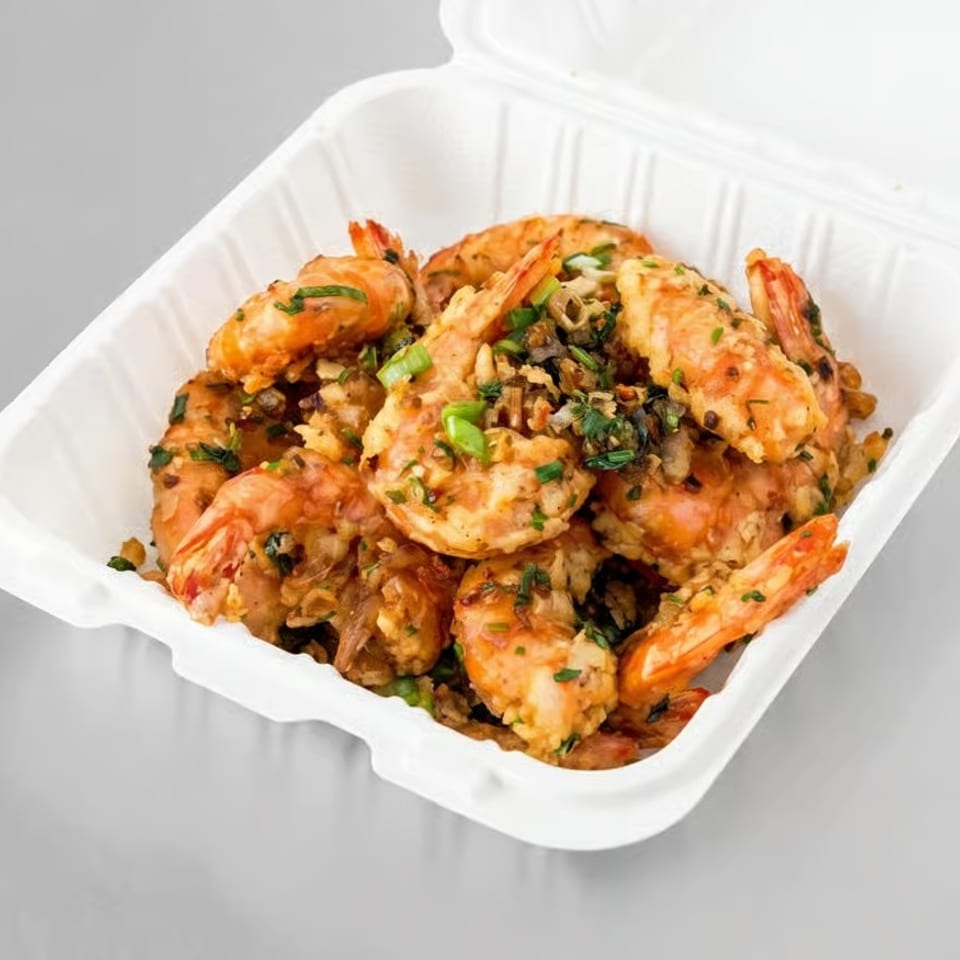 Garlic shrimp with green onions and herbs in a white takeout container.