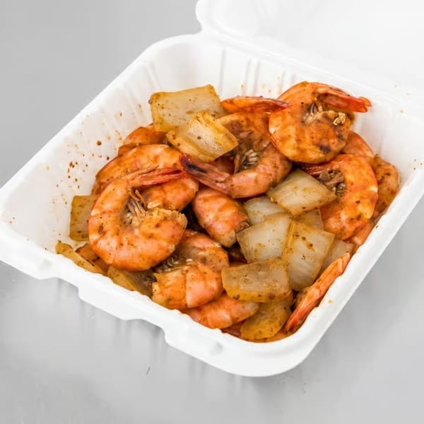Spicy shrimp and onions in a white takeout container, ready to eat.