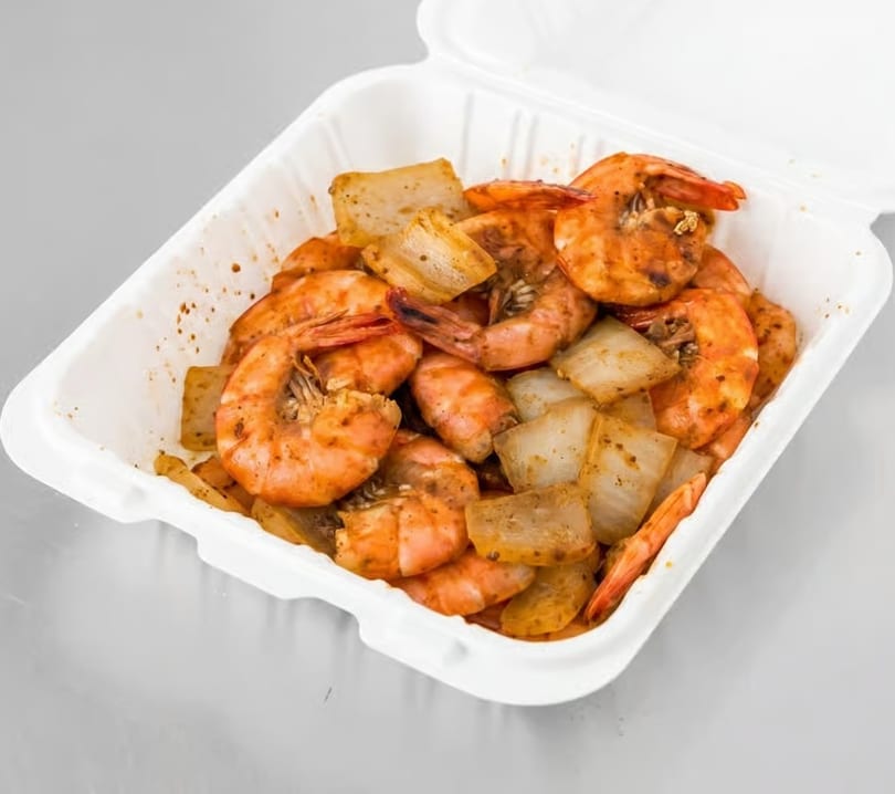Spicy shrimp and onions in a white takeout container, ready to eat.