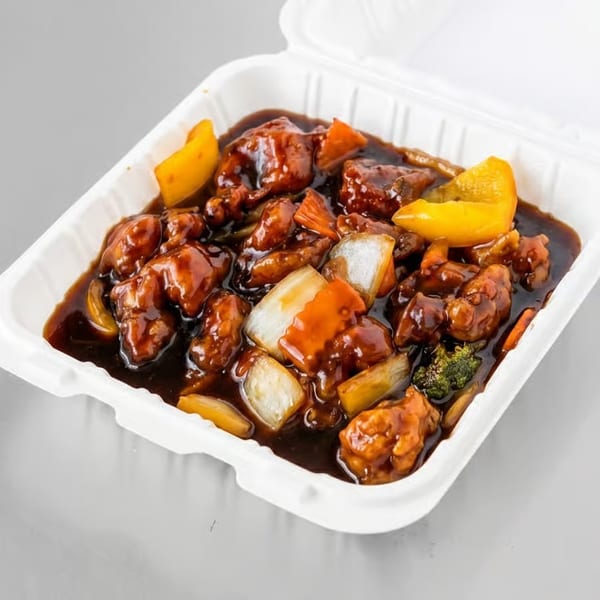 Sweet and sour chicken with bell peppers and onions in a white takeout container.